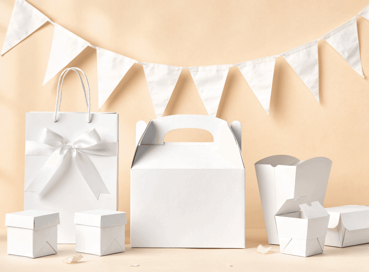 Blank white party packaging — boxes, a ribboned gift bag and bunting, ready to be customised